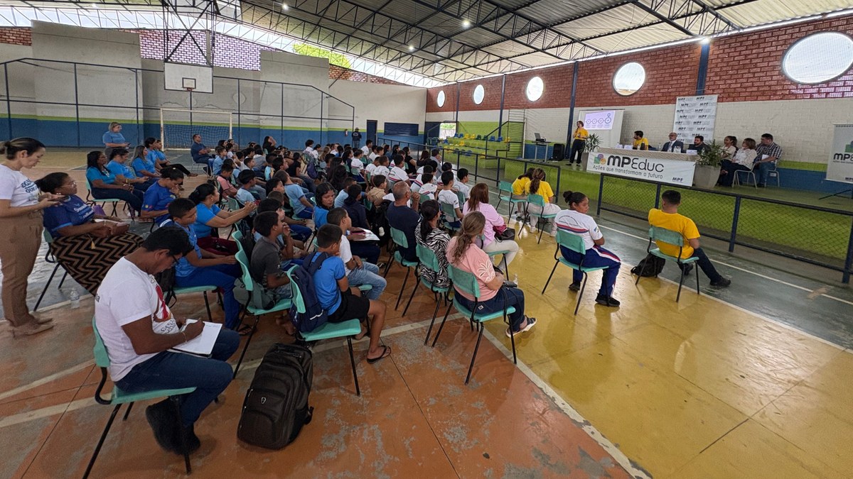 Estudantes e moradores sentados em ginásio durante escuta pública do projeto MPEduc